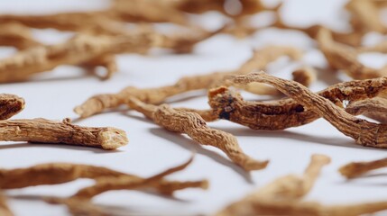 Dried, twisted root-like objects are scattered on a white surface, in soft focus