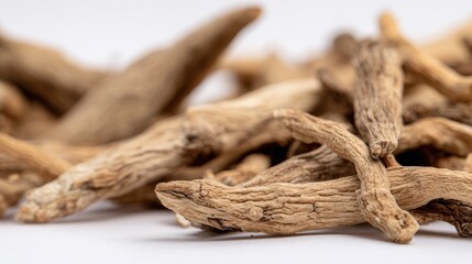 Close-up shot of a pile of dried, brown roots, showcasing texture and shape against white background