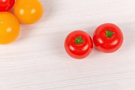 Red and yellow cherry tomatoes on a light wood surface