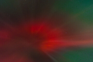 A vibrant display of red and green aurora borealis lights up the night sky.