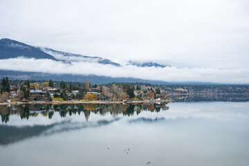 Scenic lakeside village view with tranquil water and mountain backdrop.