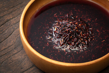 Black rice and rice water are in a wooden bowl.