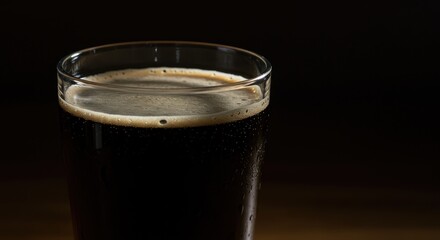 Dark Stout Beer in Glass with Creamy Head on Dark Background