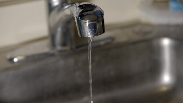 Wasting Water Concept: Running Faucet in Stainless Sink