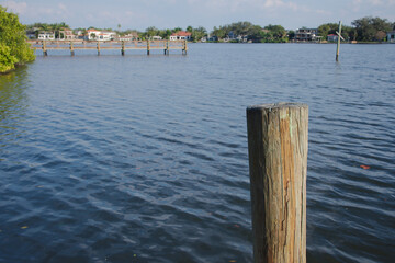 Wide angle view Coffee Pot Bay in Saint Petersburg, FL. Wood Pier in the background and white pelicans. Sunny day with blue sky and calm water. Post in foreground. 