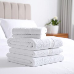 A neatly arranged stack of colorful towels sits atop a plush, neatly made bed, adding a touch of warmth and comfort to the inviting bedroom decor.
