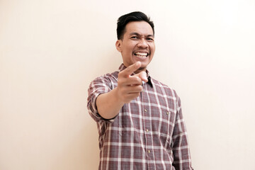 Southeast Asian man wearing flannel shirt cheerful expression while  pointing at the camera with...