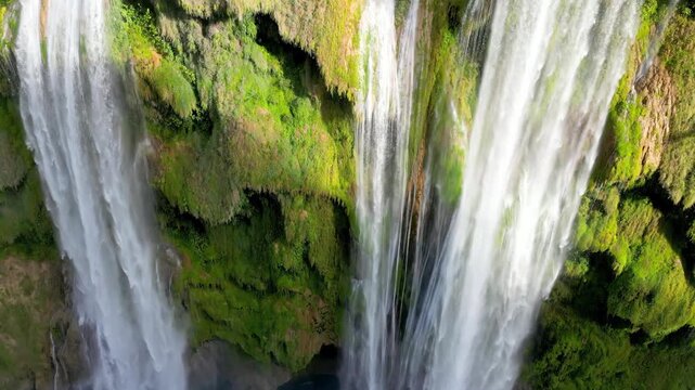 Aerial drone view of Tamul Waterfall cascading down green cliffs into a turquoise pool below