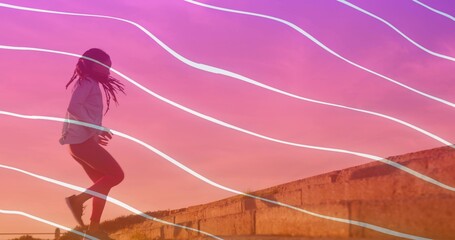 Leaping woman on concrete ledge at dusk in sportswear, shoes, grassy slope, wavy lines, copy space