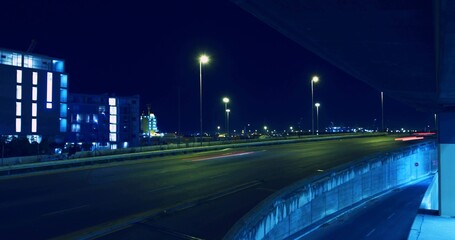 Showing multi-lane highway and curved ramp glowing under streetlights at night, with light trails