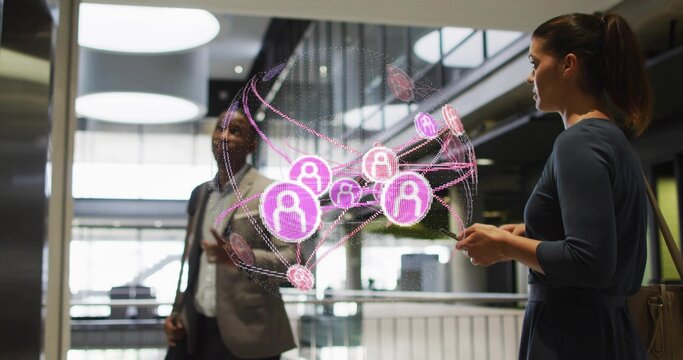 Viewing duo wearing suit and dress interacting with AR network in lobby, holding smartphone and bag
