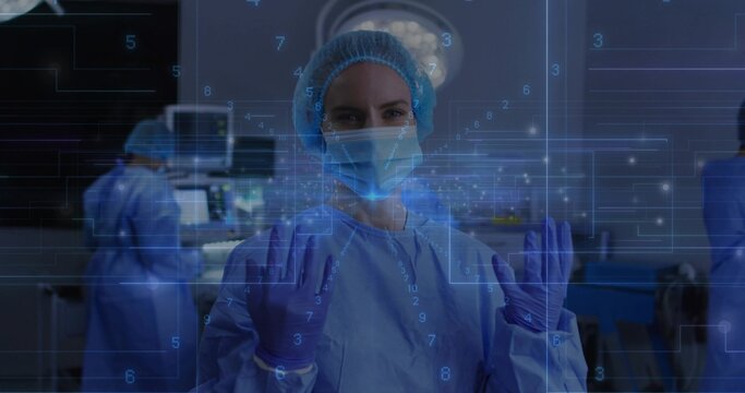 Manipulating holographic interface, lead surgeon wearing bouffant cap, mask and purple gloves in OR