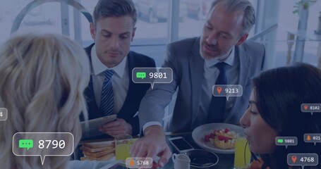 Discussing four execs wearing suits and tops sharing meal at glass lounge, holding tablet badges