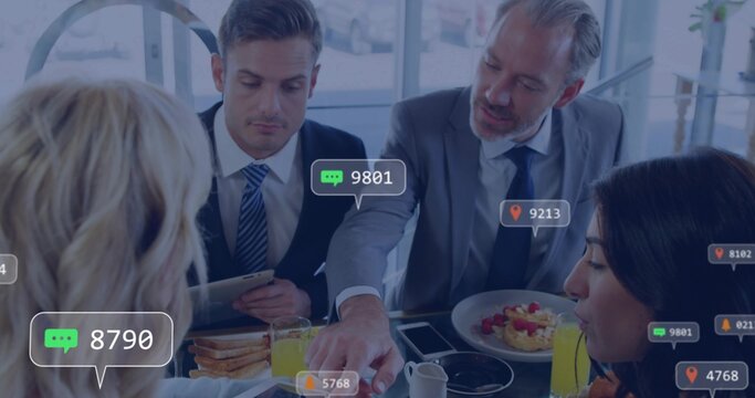 Discussing four execs wearing suits and tops sharing meal at glass lounge, holding tablet badges