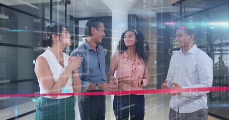 Celebrating four professionals in business-casual attire chatting in modern office, with red ribbon