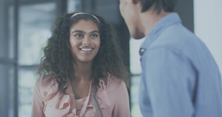 Smiling woman in pink ruffled blouse talking with man in office, microphone and glass panels