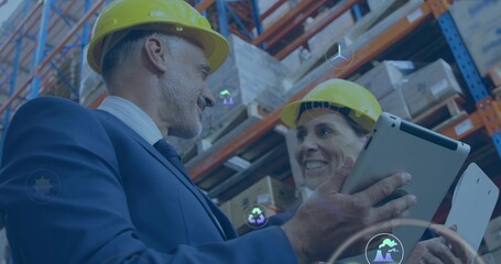 Inspecting suited manager and supervisor holding tablets at racks with yellow hard hats and icons