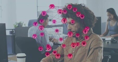 Working man wearing brown shirt focusing on computer in open office, magenta network overlay