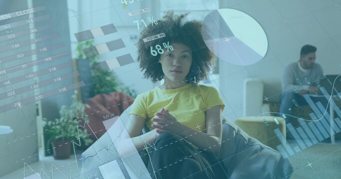 Sitting woman wearing yellow tee clasping hands at home, data overlays showing charts, percentages