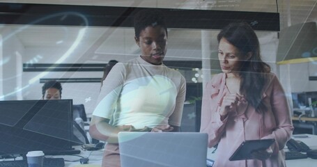 Pointing, woman in ribbed top and colleague in pink blouse reviewing laptop at office, with tablet
