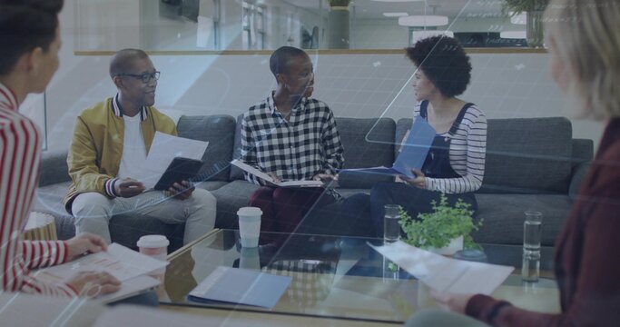 Discussing papers, five coworkers in smart casual holding blue folder and tablet in office lounge