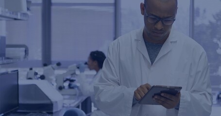 Reviewing scientist scanning tablet in lab with microscopes, white coat, glasses, copy space