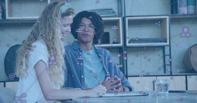 Discussing adult woman and man gesturing and writing at modern studio with notepad, digital overlay