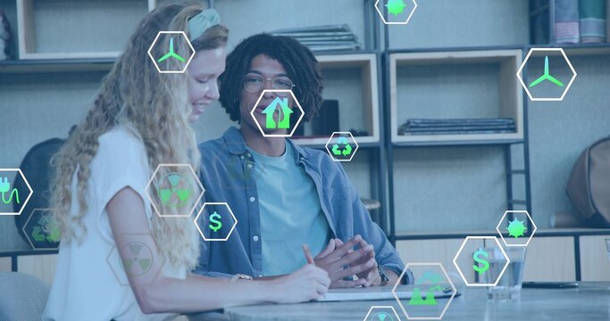 Writing woman and gesturing man collaborating at modern workspace with notebook and hexagonal icons - Powered by Adobe