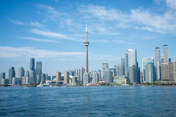 Fototapeta premium Skyline of a city with a tall tower under a blue sky on the waterfront.