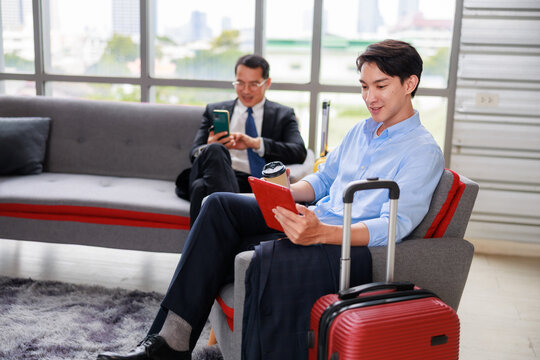 asian businessman relaxing on a lounge sofa with coffee and a digital tablet in a modern office setting, taking a break while reviewing work updates and enjoying a calm moment in a contemporary corpor