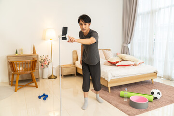 Man lifestyle home technology recording video with smartphone on tripod in bedroom