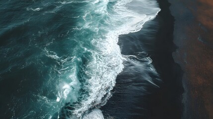 Strong turquoise waves crash against a dark sandy shoreline.
