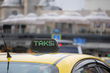 Yellow taxi with illuminated sign in busy city street