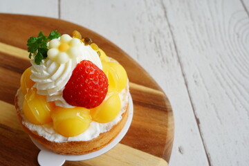 鮮やかな黄色のクリームと苺、花型チョコが可愛いフルーツタルトを撮影。カフェメニュー・季節限定新作告知・スイーツビジュアル素材に最適。爽やかな配色で明るい広告にも使いやすい一枚。