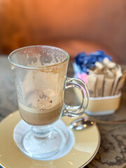 A coffee latte with a foam ln the MSC Seashore Cruise Ship Yacht Club with a blurred background.