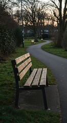 Fototapeta premium A sturdy wooden bench located adjacent to a winding paved footpath in a quiet suburban environment, providing an ideal place for peaceful rest and contemplation ,bench ,wooden ,peaceful
