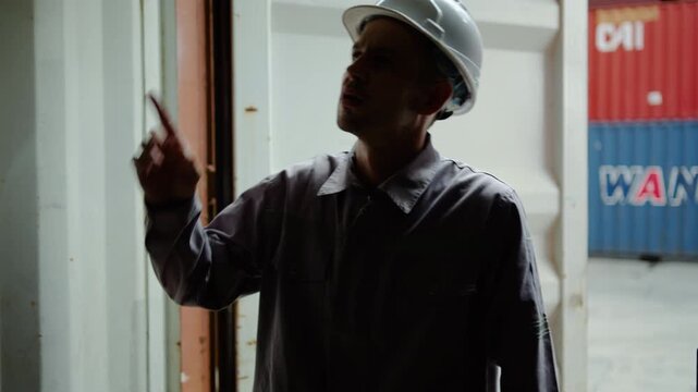 A young caucasian foreman opens a container box in a logistic warehouse, checking the cargo is neatness and organization. The focus is on secure and efficient shipping operations