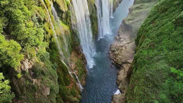 Aerial drone view of Tamul Waterfall cascading down green cliffs into a turquoise pool below