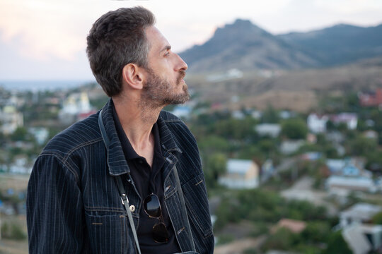 dreamy man with beard in profile against backdrop of mountains