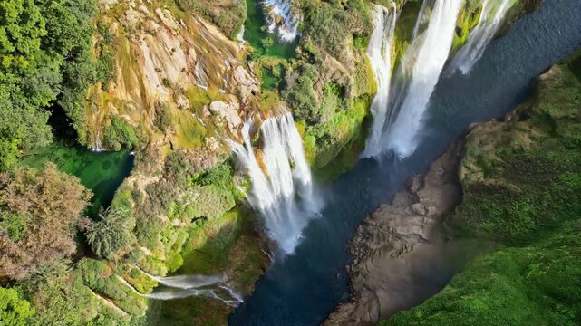 Aerial drone view of Tamul Waterfall cascading down green cliffs into a turquoise pool below
