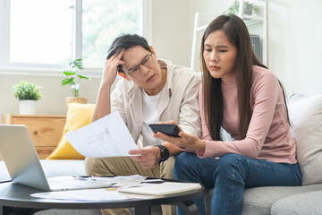 Fototapeta premium Stressed financial owe asian young couple love sitting suffer, stressed and confused by calculate expense from credit card bill, no money to pay, mortgage or loan. Debt, bankrupt or bankruptcy people.