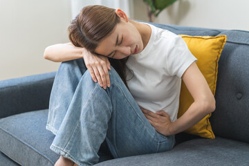 Sick asian young woman in pain, hand holding belly, stomach pain from food poisoning, girl hurt...