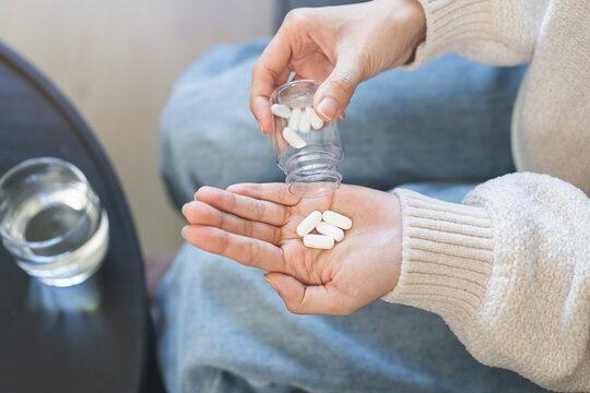 Fototapeta Sick asian young woman, girl holding tablet pill on hand pouring drug from medication bottle, painkiller medicine from stomach pain, head ache, pain for treatment, take drug or vitamin, health care.