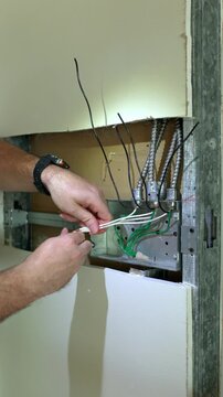 Electrician wiring a light switch inside a metal junction box USA