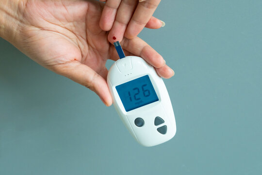 Woman's hands checking diabetes and hyperglycemia with digital blood sugar meter. Healthcare and medical concept