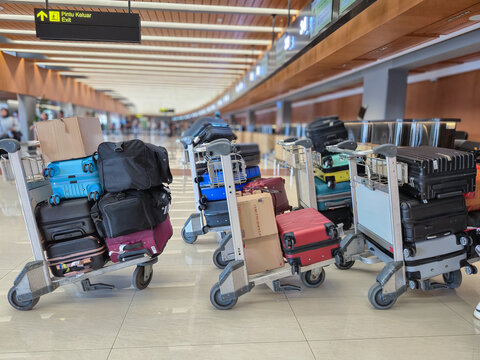trolleys with piles of suitcases and cardboard boxes are queuing and being weighed before being put into the plane's baggage compartment.