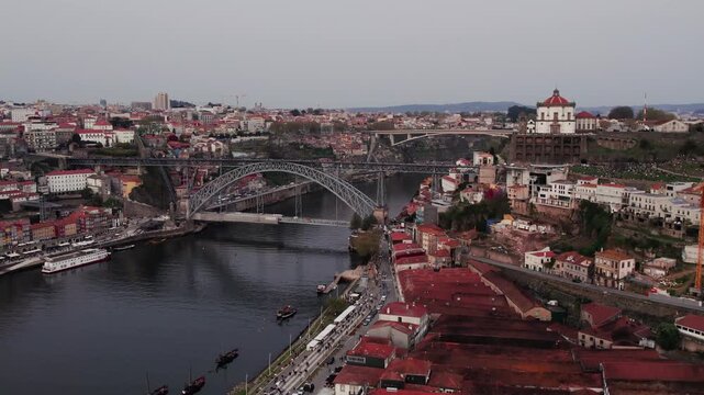 Porto cityscape showcasing traditional buildings, historic bridge spanning Douro River, and a famous church crowning the hillside, depicting urban life and travel destinations, drine ascend pull away