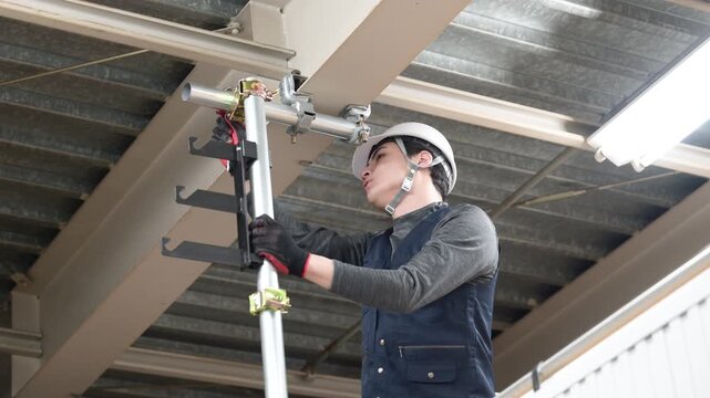 天井が近い高所の足場で単管パイプを固定するクランプなどの施工作業の動画　鳶職や作業員のイメージ　レンチで締める