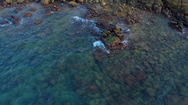Clear turquoise ocean water washing over colourful rocks on Koh Rong island Cambodia