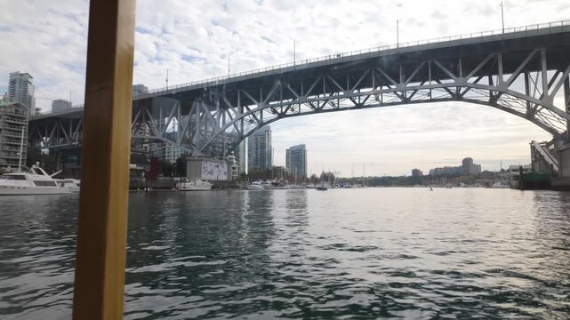 Boat POV shot traveling underneath the Granville Bridge on the False Creek Ferry in Vancouver, British Columbia, Canada. 4K